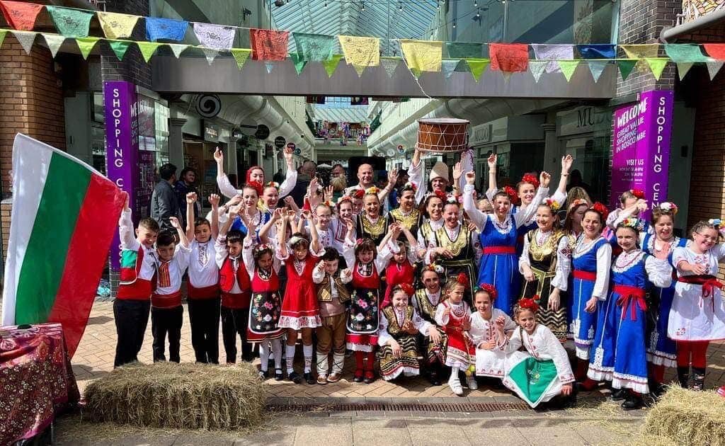 Increase the Peace — a folk dance group in traditional dress with a Bulgarian flag