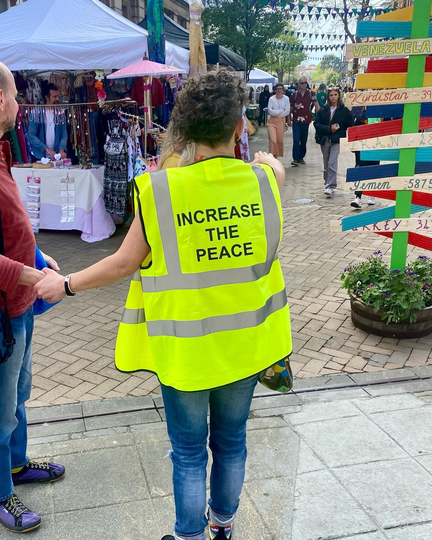 Increase the Peace — a volunteer in a branded hi-vis vest on the high street