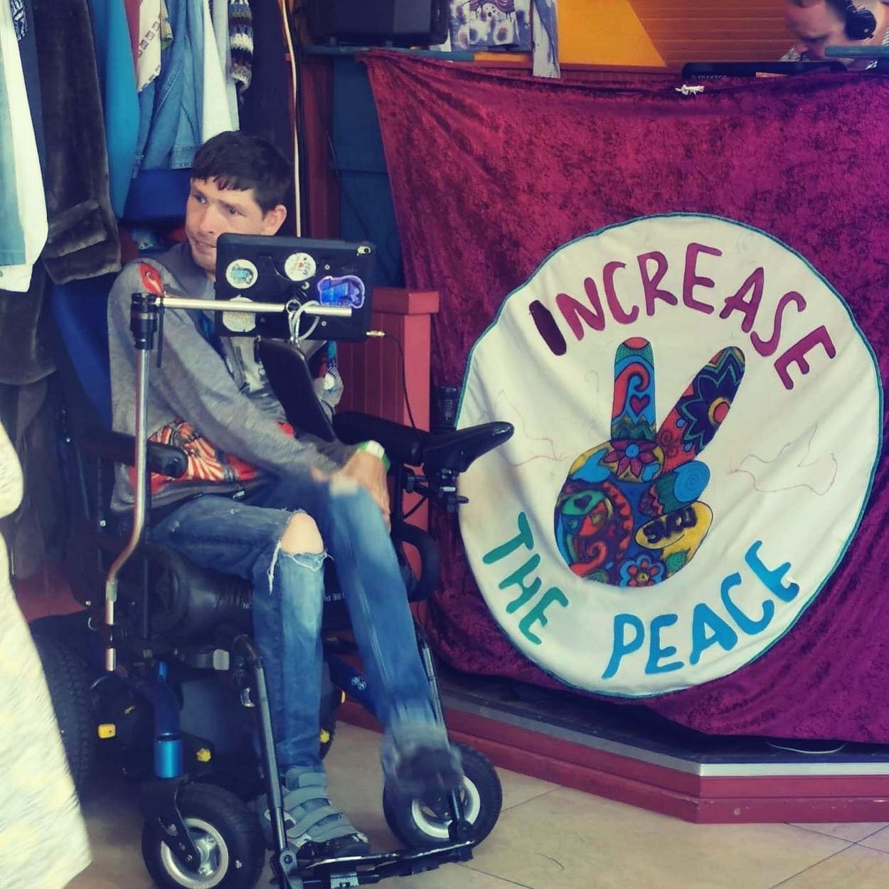 Increase the Peace — a visitor beside the hand-painted Increase the Peace banner