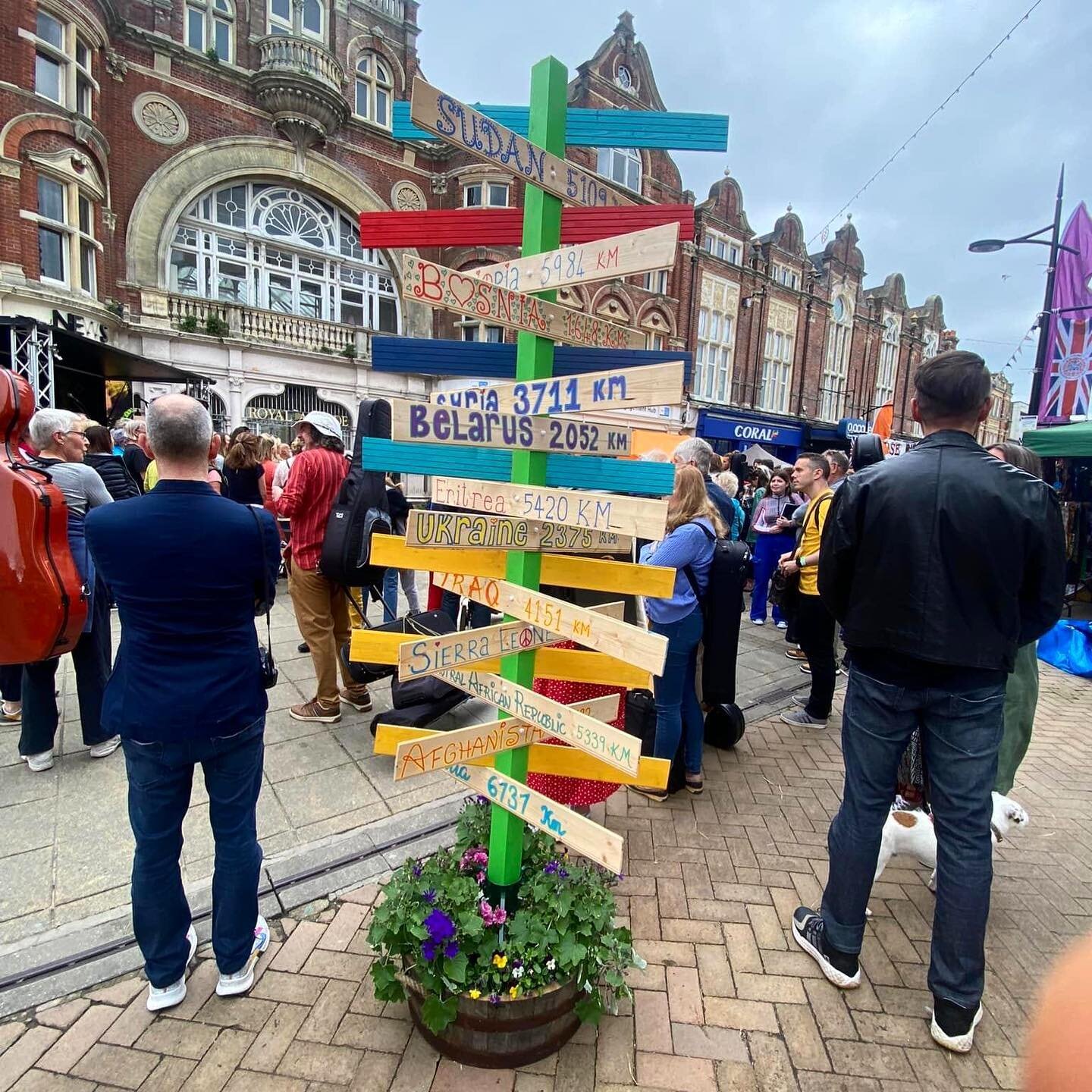 Increase the Peace — crowd around the distances signpost on Boscombe High Street