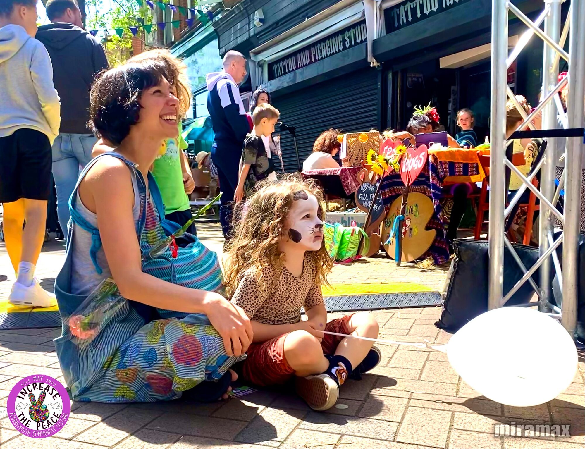 Increase the Peace — a woman and a face-painted child watching a performance